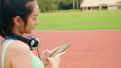 Estilo-de-vida-asiático-deporte-mujeres-sosteniendo-teléfono-inteligente-reproducir-música-relajación