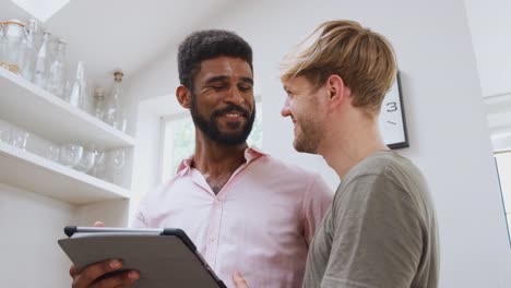 Pareja-gay-masculina-usando-tableta-digital-en-casa-en-la-cocina-juntos