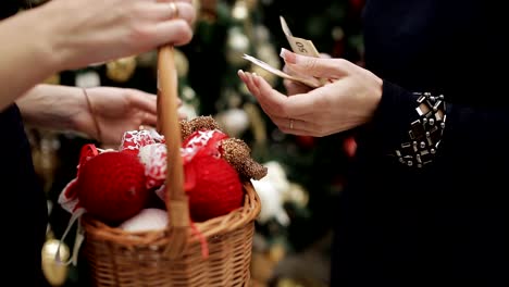 Comprar-adornos-navideños-en-la-tienda.-El-comprador-cuenta-y-da-el-dinero-al-vendedor-y-recibe-a-cambio-una-cesta-de-bolas-de-Navidad.