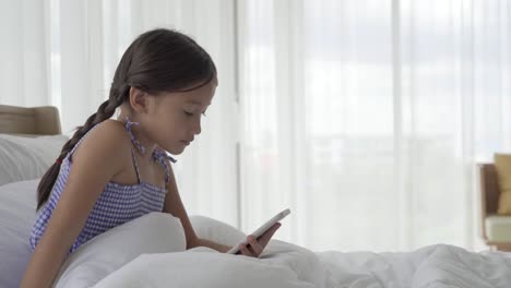 Asiatische-Mädchen-mit-Smartphone-im-Schlafzimmer