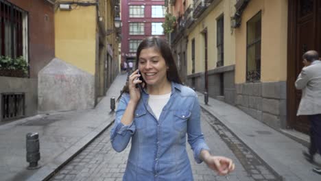 Happy-attractive-young-woman-using-smart-phone-texting-message-and-chatting-calling-friends-while-walking-on-city-street-urban-background.