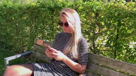 beautiful-blonde-sits-on-a-bench-via-chat-on-the-phone