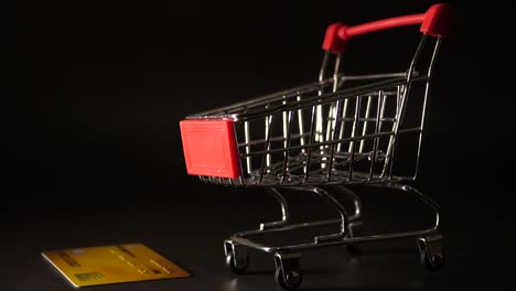 Credit-card-falling-down-on-mini-shopping-cart