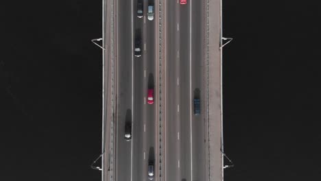 Bridge-highway-dark-water-colorful-cars-in-traffic-aerial-top-view