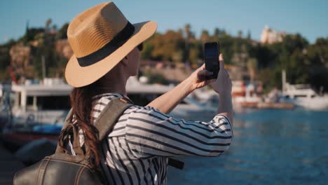 Millennial-hipster-mujer-turista-en-traje-casual-con-mochila-fotografiando-en-marina