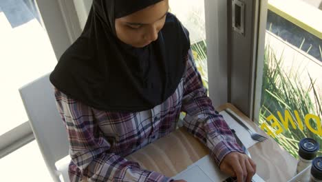 Young-woman-using-laptop-in-a-cafe