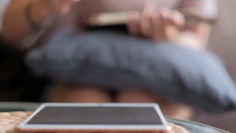 Closeup-of-tablet-and-woman-writing-a-book-in-blurred-background.