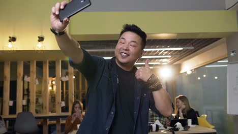 Hipster-männliche-Arbeiter-machen-Selfie-auf-dem-Smartphone-auf-modernen-Büro-Hintergrund