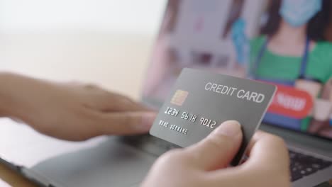 Close-up-consumer-woman's-hand-holding-credit-card-making-e-bank-online-payment-for-purchase-in-online-website-store-with-laptop-computer.-Ecommerce-website-payments.-new-normal-digital-lifestyle