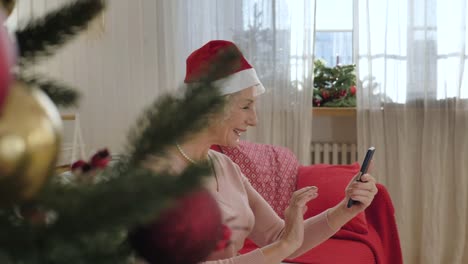 Elderly-woman-with-Santa-Claus-hat-on-head-enjoys-video-call