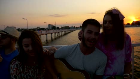 Boys-and-girls-sitting-on-a-bench-and-singing-on-a-pontoon