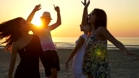 Vier-Freunde-tanzen-am-Strand-in-der-Abenddämmerung