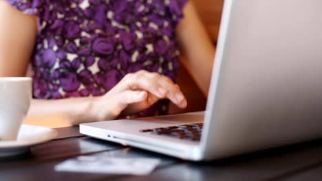 Frau-mit-Laptop-in-einem-Café-arbeiten.