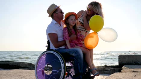 lover-disabled-with-family,-handicapped-parents-with-child-open-air,-happy-daughter-sitting-on-dad-with-balloons-in-hand,-pregnant-woman-with-little-girl