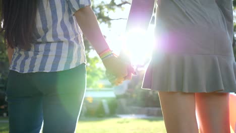 close-up-of-an-unrecognizable-young-women-with-LGBT-bracelet-in-backlight-stand-in-park