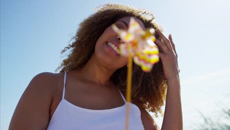 Portrait-of-Ethnic-female-with-windmill-on-beach