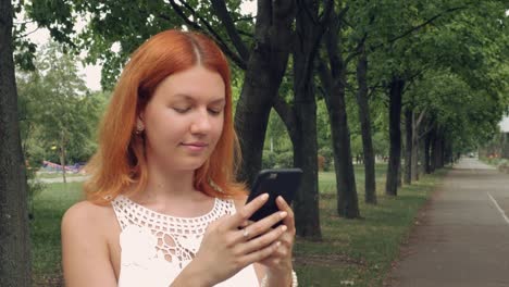 ginger-student-using-smart-phone-outdoor.