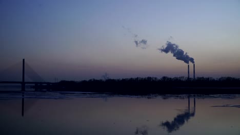 The-smoky-plant-on-the-background-of-the-river-and-the-setting-sun