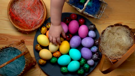 Child's-hand-takes-and-lays-colored-easter-eggs-in-different-baskets