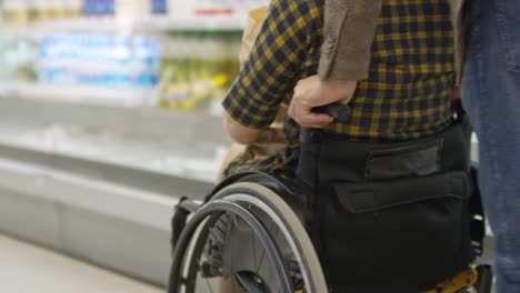 Man-Pushing-Disabled-Woman-in-Wheelchair-in-Grocery-Store