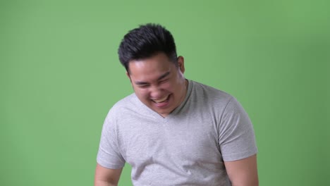 Young-handsome-overweight-Asian-man-against-green-background