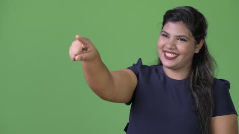 Young-overweight-beautiful-Indian-businesswoman-against-green-background