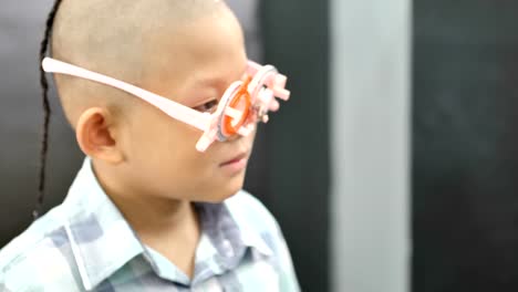 eyesight-check.-Asian-boys-who-have-vision-disabilities.-Left-eye-is-not-visible-from-brain-surgery.-Medical-treatment-and-Rehabilitation.-video-4k