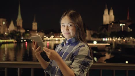 Young-Asian-woman-using-tablet-in-the-city-streets