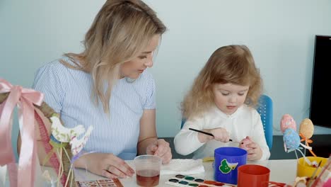 Madre-y-su-pequeña-hija-pintando-huevos-de-Pascua