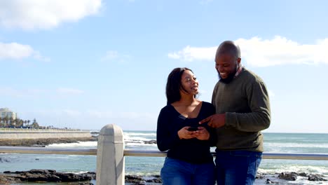 Happy-couple-using-mobile-phone-near-railing-on-a-sunny-day-4k