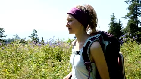 Happy-woman-tourist-in-a-hike-goes-with-a-backpack-and-smiles,-slow-motion,-camera-movement