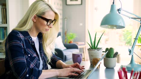 Attraktive-blonde-Geschäftsfrau-Tippen-auf-Laptop-zu-Hause-Büro