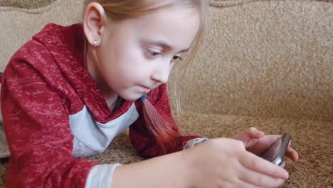 Girl-teenager-watching-a-video-in-the-phone-while-lying-on-the-couch.