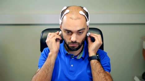 Un-hombre-con-ondas-cerebrales-exploración-auricular-trabajando-con-la-computadora.