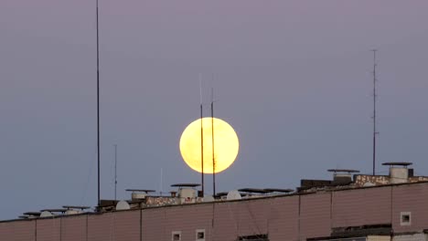 La-gran-luna-llena-sobre-el-tejado-de-un-edificio-Multistory-se-está-moviendo-hacia-arriba