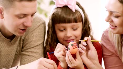 hija-sosteniendo-huevo-de-Pascua,-y-los-padres-de-cerca-lo-decoraron.