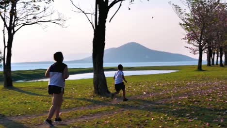 Eine-fette-asiatische-Frau-joggt-abends-in-natürlichem-Sonnenlicht,-zusammen-mit-seinem-Sohn-läuft.--Für-gute-Gesundheit.-Zeitlupe