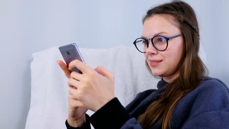 Feliz-joven-morena-mujer-en-gafas-tipo-un-mensaje-en-un-teléfono-móvil.