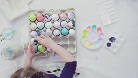 Niña-pequeña-pintando-huevos-de-Pascua-con-pintura-acrílica.