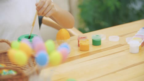 Creative-boy-is-painting-an-Easter-egg-in-an-yellow-colour-with-a-help-of-paint-brush.