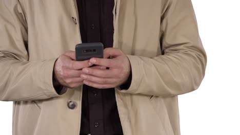 Man-in-trench-coat-using-mobile-smart-phone-on-white-background