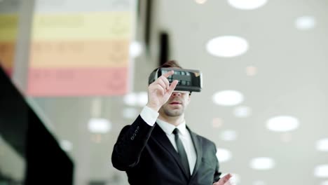 Panning-medium-shot-of-middle-aged-businessman-in-suit-wearing-virtual-reality-headset-and-browsing-data