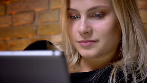 Nahaufbau-Porträt-der-jungen-Frau-mit-blonden-Haaren-auf-dem-Tablet-im-Inneren-in-gemütlicher-Wohnung