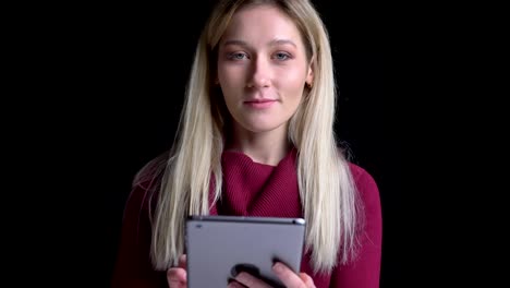 Closeup-shoot-of-young-pretty-caucasian-female-using-the-tablet-then-looking-at-camera-with-background-isolated-on-black