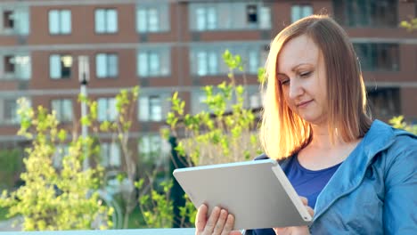 Frau-mit-Tablet-Computer-sitzt-auf-Bank-in-der-Stadt