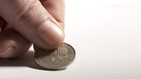 Hand-putting-2-Deutsche-Mark-coin-on-desk.-Obverse-side-showing-eagle