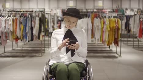 Mujer-discapacitada-con-teléfono-en-la-tienda-de-ropa