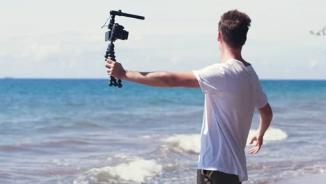 Young-male-vlogger-filming-travel-story-on-the-beach.