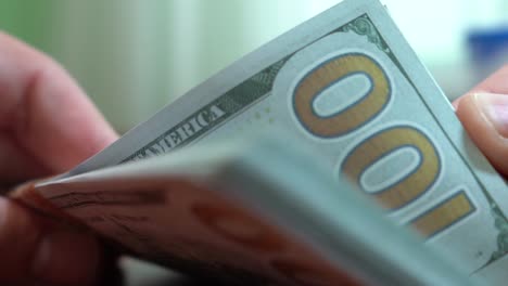 Fingers-sorting-through-a-stack-of-banknotes.-A-stack-of-$-100-bills.-Close-up.-Counterfeit-money.