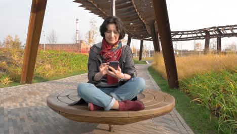 Caucasian-woman-riding-small-carousel-in-circle-Holding-cellphone-in-her-hands